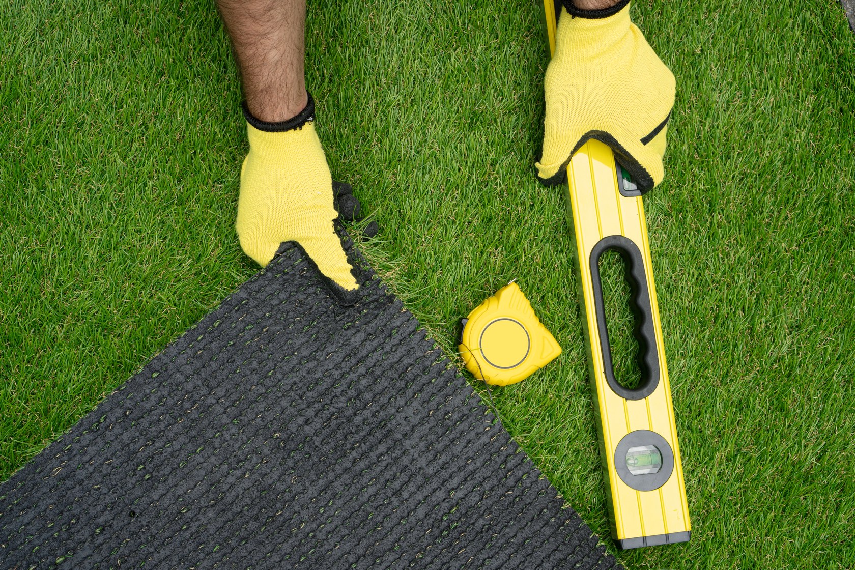Bright green artificial turf being installed and trimmed